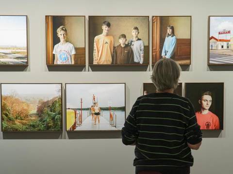  – Eine Besucherin steht rechts im Bild und schaut sich Fotografien in der Ausstellung an.