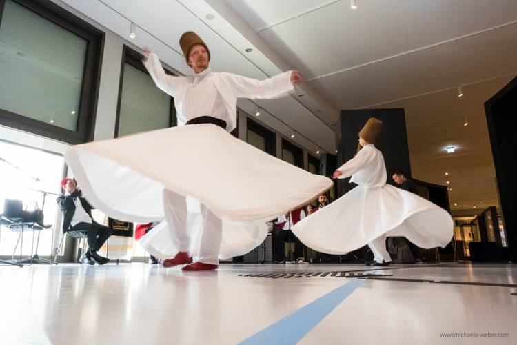 Veranstaltung „Mystische Dimensionen - Auf den Spuren berühmter Sufis" im Humboldt Forum – Zwei tanzende Personen in tradioneller weißer Kleidung