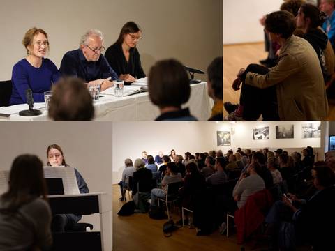  – Drei Personen sitzen an einem Tisch mit Mikrofonen und lesen vor Publikum. Zuschauer*innen in einem Raum mit Bildern an den Wänden.