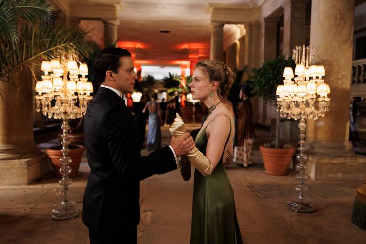 Still aus der Amazon-Serie „Miss Sophie“ – Still aus der Amazon-Serie „Miss Sophie“: Butler James (Kostja Ullmann, links) und Miss Sophie (Alicia von Rittberg, rechts) auf einer Party in der Pflanzenhalle des Orangerieschlosses