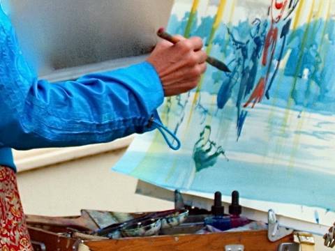  – Person mit Pinsel vor einer bereits – vorwiegend blau – bemalten Leinwand