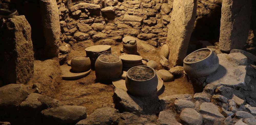 Steingefäße, Platten und Klopfsteine in Fundlage in einem Küchenbereich in Karahantepe, 9400–8000 v.Chr.