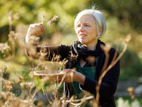 Im Museumsdorf gibt es viele Kräuter. – Frau mit einer Ernteschale und Kräutern im Musuemsdorf