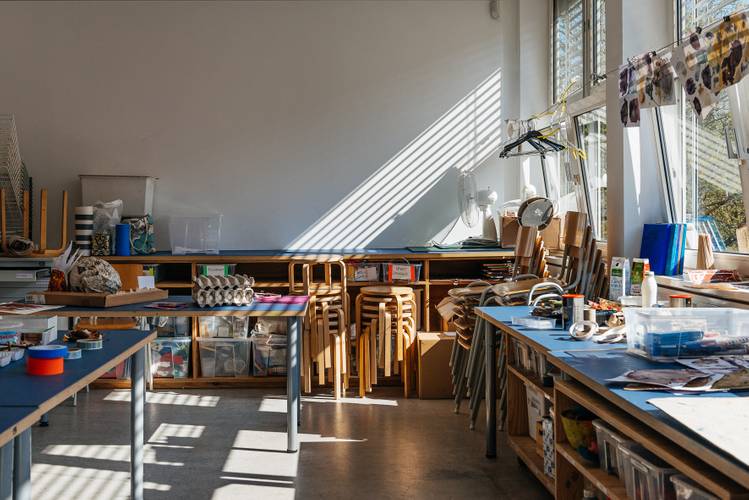 Atelier Bunter Jakob in der Berlinischen Galerie – Foto des sonnendurchfluteten Atelier Bunter Jakob mit Hocker-Stapeln, Arbeitstischen und Kreativ-Material.