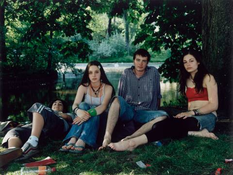 Rineke Dijkstra, Vondelpark, Amsterdam, June 10, 2005 – Fotografie: Vier junge Personen sitzen bzw. liegen in Sommerkleidung in einem Park. Ihr direkt ist direkt in die Kamera gerichtet.