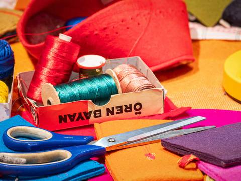  – Näh- und Bastelmaterialien: bunte Garnrollen, Schere, Filzstücke, rote Schachtel, gelbe runde Dose. Text auf Schachtel: "OBER BAVAN".