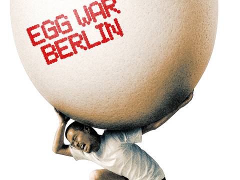  – Eine kniende Person trägt ein übergroßes Ei auf den Schultern. Auf der Eierschale steht in roter Schrift „EGG WAR BERLIN“ vor weißem Hintergrund.