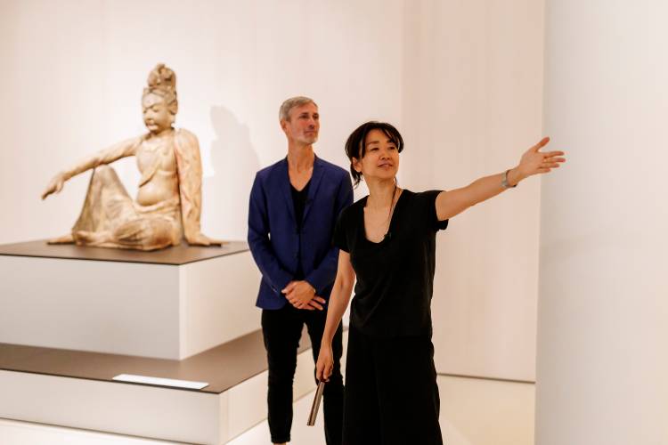 Führung Un-sichtbare Hände im Museum für Asiatische Kunst – Eine Frau erklärt eine Buddha-Statue in einem Kunstmuseum, während ein Mann interessiert zuhört.
