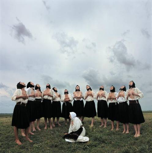 Marina Abramović, Women Massaging Breasts aus der Serie Balkan Erotic Epic, C-Print, 2005, Serbia – Frauen mit schwarzen Kopftüchern und knielangen Röcken massieren ihre nackten Brüste. Dabei schauen sie in den Himmel.