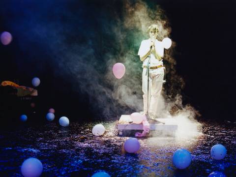 Archives of Feelings – Person steht in einem Lichtkegel auf einer Bühne, umgeben von Ballons und Nebel.