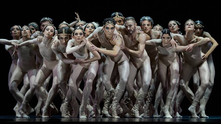 2 Chapters Love – Ballettgruppe auf der Bühne, alle tragen hautfarbene Trikots und Stirnbänder, eng zusammen, verschiedene Posen und Gesichtsausdrücke, dunkler Hintergrund.