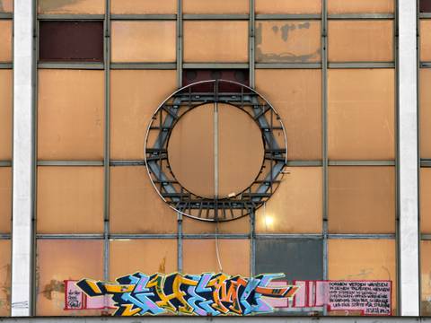 Leere Halterung des Staatsemblems am geschlossenen Palast der Republik – Fassade mit kreisfoermiger Metallstruktur in der Mitte. Darunter buntes Graffiti und Text: "Darueber werden waechsen in ihnen..."