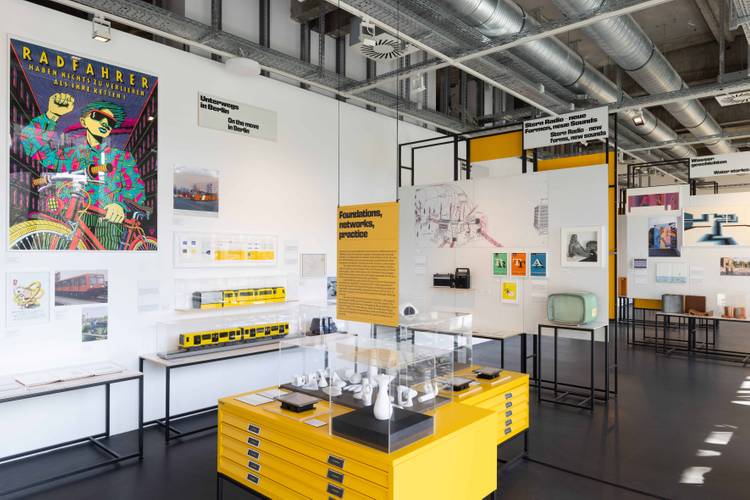 Ausstellungsansicht „Gestalten für Berlin. Design aus der Kunsthochschule Berlin-Weißensee“ – Ausstellungsansicht mit verschiedenen Exponaten, sowie großformatigen historischen Fotografien und Plakaten