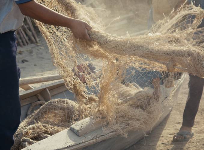 Daniel Asadi Faezi & Mila Zhluktenko, Aralkum, 2022 – Filmstill: Nahaufnahme eines Fischerei-Netzes, das von zwei Personen gehalten wird.