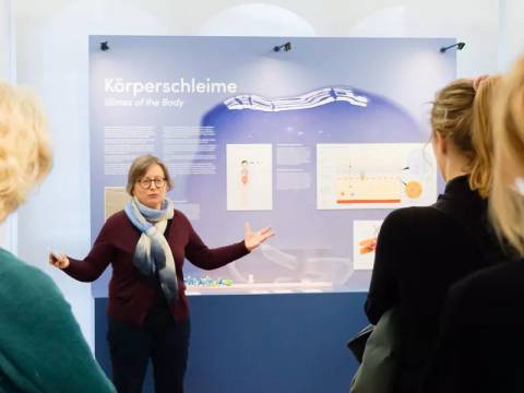 Vermittlerin vor Ausstellungswand Körperschleime