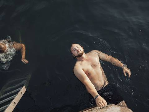 Malte aus der Serie „Bleiben“ – Ein junger Mann in Badehose schwimmt auf dem Rücken.