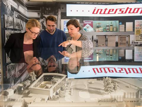 Besucherinnen und Besucher am Modell des Tränenpalastes – Eine Gruppenbegleiterin erklärt das Modell des Tränenpalastes