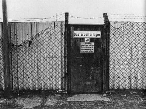 Gastarbeiterlager, Ruhrgebiet, 1974 – Stacheldrahtzaun mit Wellblechwand und Tür mit Aufschrift "Gastarbeiterlager"