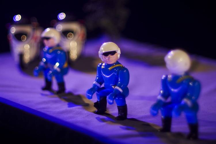 Blue – Drei Spielzeugfiguren in blauen Uniformen und Helmen, unscharf im Hintergrund zwei Spielzeug-Motorräder.