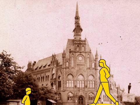 „Geschichte vor Ort II“ – Zwei gelbe Figuren laufen vor dem historischen Rathaus Lichtenberg hin und her.