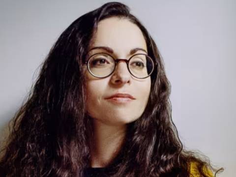 Marina Chernivsky – Eine Person mit langen, lockigen Haaren und Brille trägt einen gelben Pullover. © Jan Zappner.