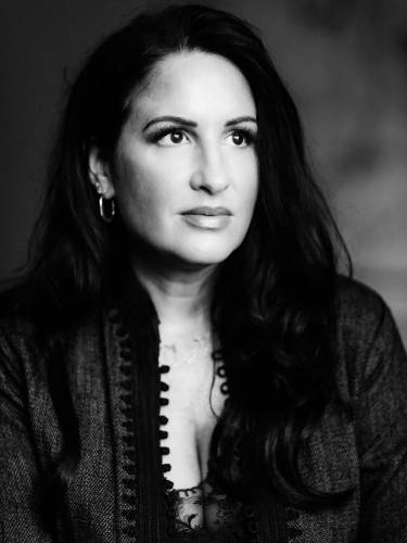 Minu Barati "Unsere Väter" – Person mit langen Haaren blickt weg. Schwarz-weiße Aufnahme, strickähnliches Oberteil mit Spitze darunter. Dezente Ohrringe.
