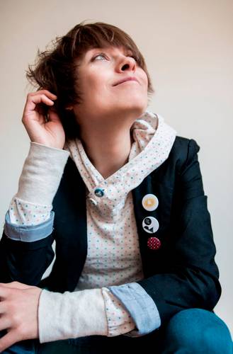 Theresa Hahl – Person mit kurzem Haar trägt Punktmuster-Hoodie, Blazer mit drei Buttons, blickt leicht lächelnd nach oben.