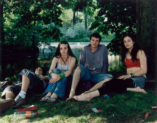 Rineke Dijkstra, Vondelpark, Amsterdam, June 10, 2005 – Fotografie: Vier junge Personen sitzen bzw. liegen in Sommerkleidung in einem Park. Ihr direkt ist direkt in die Kamera gerichtet.