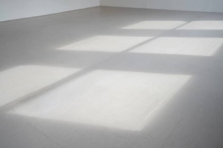 Gianna Surangkanjanajai, Removed, 2025, Courtesy die Künstlerin – Grauer Boden, darauf zeichnen sich durch Licht die Formen dreier Fenster ab