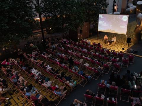  – Foto: Blick von schräg oben auf ein Open Air-Screening auf dem Vorplatz der Berlinischen Galerie. Viele Menschen sitzen auf Liegestühlen vor einer großen Leinwand.