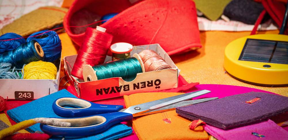 Näh- und Bastelmaterialien: bunte Garnrollen, Schere, Filzstücke, rote Schachtel, gelbe runde Dose. Text auf Schachtel: "OBER BAVAN".