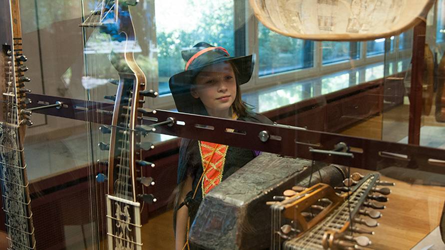 Kind in historischem Kostüm vor einer Vitrine mit Lauten – Kind in historischem Kostüm vor einer Vitrine mit Lauten