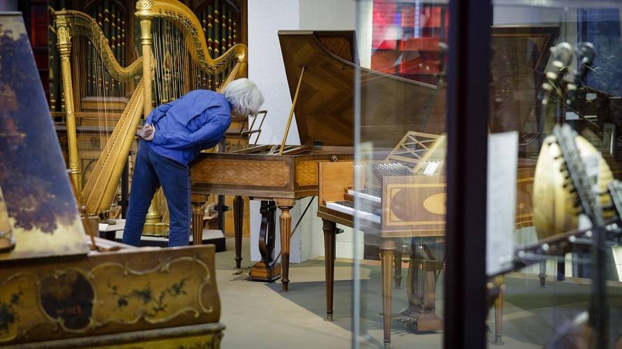 Besucher im Museum – Besucher im Museum bei der Betrachtung eines Cembalos