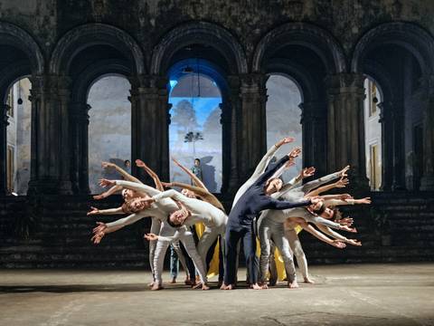 “Dialoge 2013 – Kolkata”, Sasha Waltz & Guests – Tanzensemble in synchron gebogener Pose in einer historischen Halle mit beleuchtetem Hintergrund.