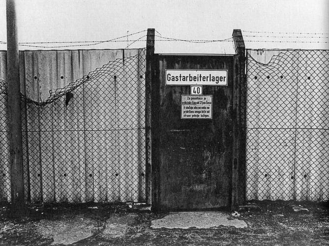 Gastarbeiterlager, Ruhrgebiet, 1974 – Stacheldrahtzaun mit Wellblechwand und Tür mit Aufschrift "Gastarbeiterlager"