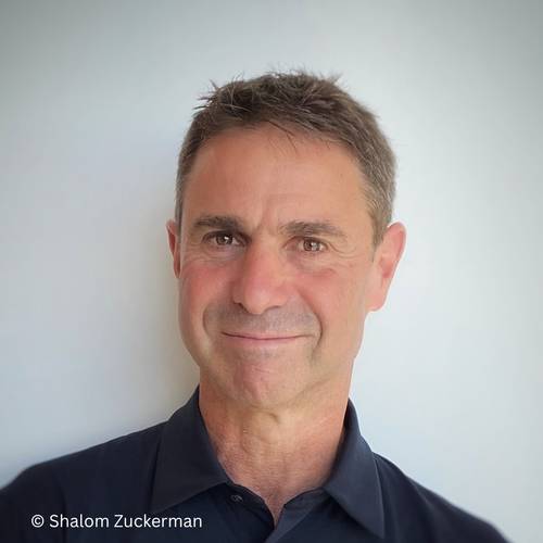 Shalom Zuckerman – Person mit kurzen, dunklen Haaren in schwarzem Hemd vor hellem Hintergrund. © Shalom Zuckerman