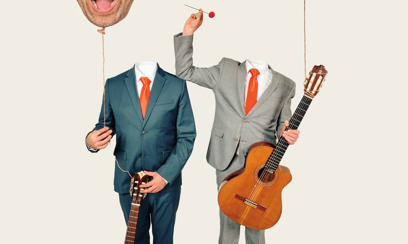 Simon & Jan – Zwei kopflose Personen im Anzug mit roten Krawatten und Gitarren. Der eine haelt einen roten Ballon mit Kopf, der andere einen Stock mit roter Kugel.