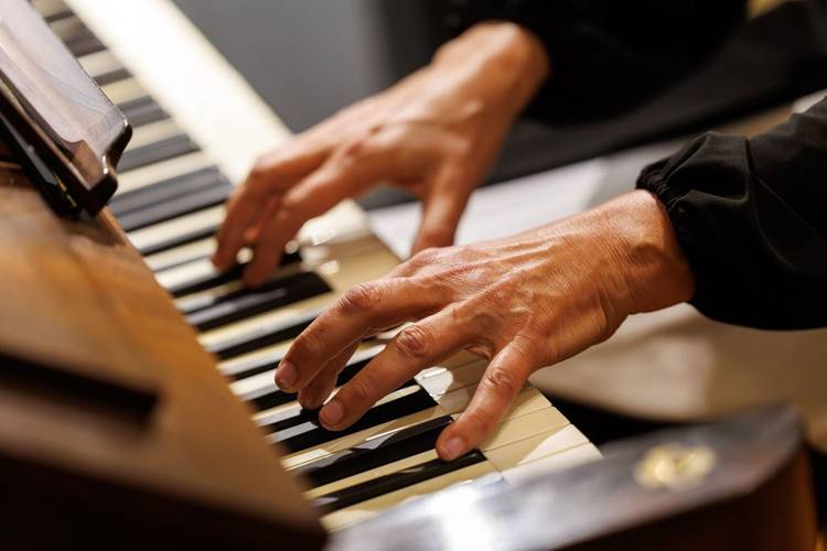Orgelmusik als Brücke zwischen Vergangenheit und Gegenwart. – Nahaufnahme der Hände eines Organisten beim Orgelspielen