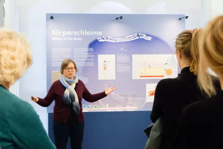 Vermittlerin vor Ausstellungswand Körperschleime
