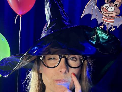 Das Grusical – Person mit schwarzem Hexenhut und Brille, denkt nach. Roter und gruener Ballon im Hintergrund. Zeichentrickfledermaus in Streifen-Shirt oben rechts.