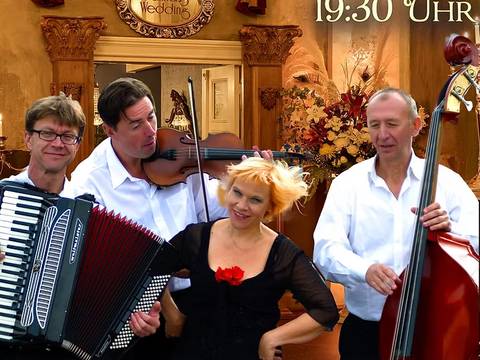 odessa express – Vier Personen in weißen Hemden. Eine spielt Akkordeon, eine Geige, eine Kontrabass. Hintergrund: Blumendeko, Text: "Ballhaus Wedding, 8.10. 19:30 Uhr, Berlin