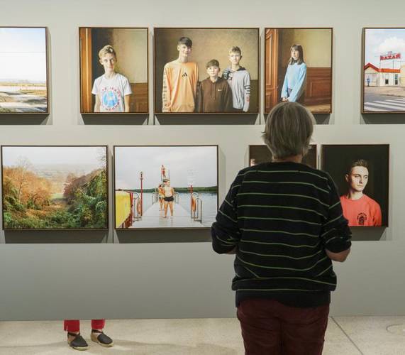 Eine Besucherin steht rechts im Bild und schaut sich Fotografien in der Ausstellung an.