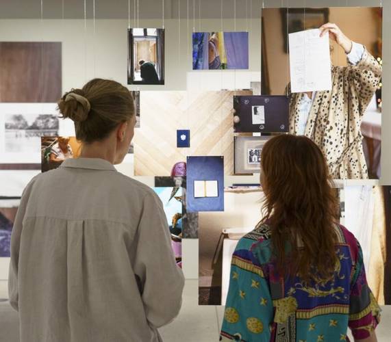 Zwei Besucherinnen sehen sich Fotografien in der Ausstellung an und sind von hinten zu sehen.