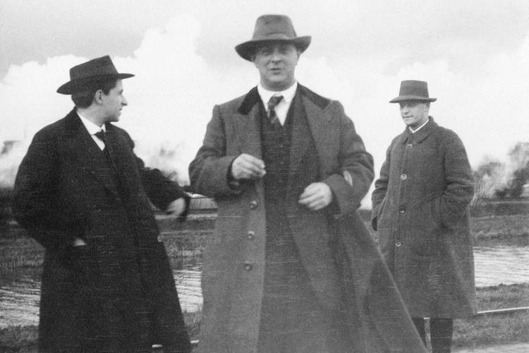 Wie heißt diese Band? Die Komponisten Erwin Stein, Arnold Schönberg und Anton Webern bei einem Spaziergang, 1914 – Drei Männer in Mänteln vor einem Kanal, der mittlere schaut in die Kamera