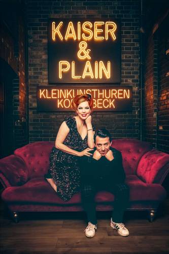 KAISER & PLAIN – Zwei Personen auf rotem Sofa, eine im glitzernden Kleid, eine in dunkler Kleidung. Leuchtschrift: KAISER & PLAIN, KLEINKUNSTHUREN KOTTBÄCK.
