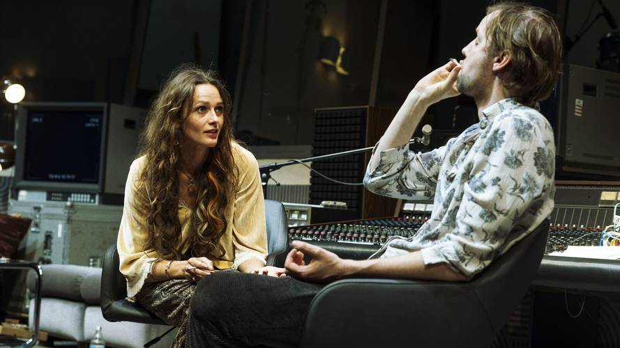 Stereophonic – Zwei Personen in einem Tonstudio, eine im langen gelben Shirt, die andere mit floralem Hemd, sitzen vor einem Mischpult und reden miteinander.