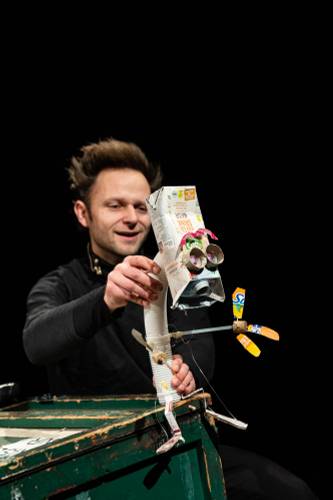 Eine Person hält eine Roboterfigur aus Recyclingmaterialien, einschließlich eines Tetrapaks mit der Aufschrift "Kuh Kinder Milch" als Kopf.