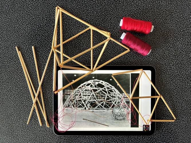 Foto: Cornelia Durka – Im Bild ist ein Tablet mit der Abbildung eines historischen Schwarz-Weiß-Fotos zu sehen. Es handelt sich um das Foto mit der Arbeit „Pentahexaedron“ (1948) des Künstlers Richard Buckminster Fuller. Ansonsten um das Tablet herum sind rotes Garn und einige Strohstern-ähnliche Formen zu sehen, die dreimensional sind und noch unfertig erscheinen.