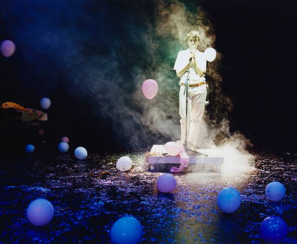 Archives of Feelings – Person steht in einem Lichtkegel auf einer Bühne, umgeben von Ballons und Nebel.