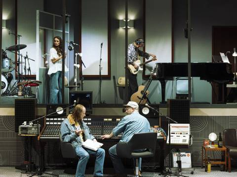 Stereophonic – Tonstudio mit Musiker*innen: Schlagzeuger, Saengerin, Bassist, Pianistin. Im Studio Regieplatz mit zwei Personen an einem Mischpult. Gitarren im Hintergrund.
